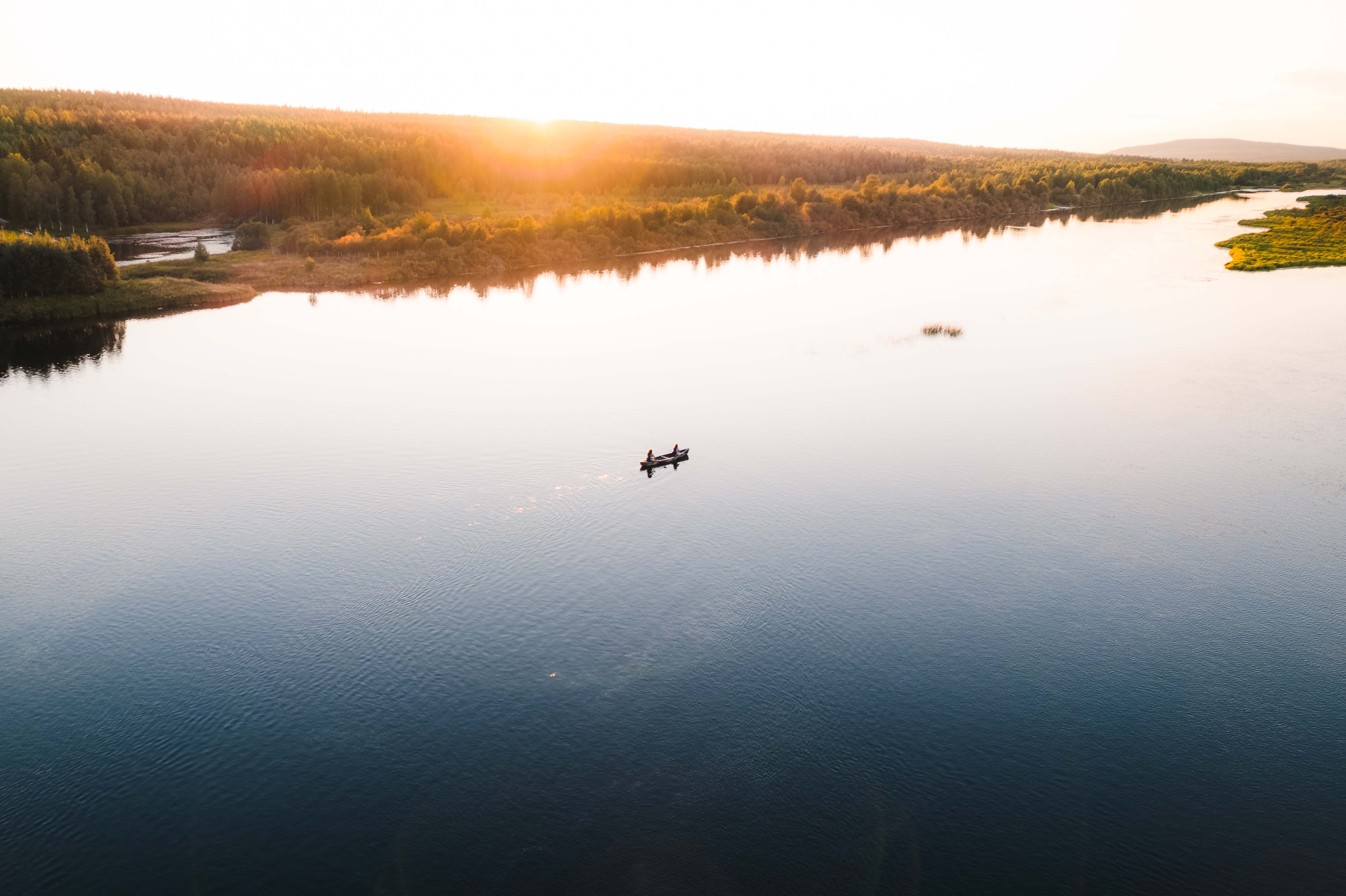 Ein Ruderboot mit zwei Personen auf einem See in der Abendsonne aus der Vogelperspektive.