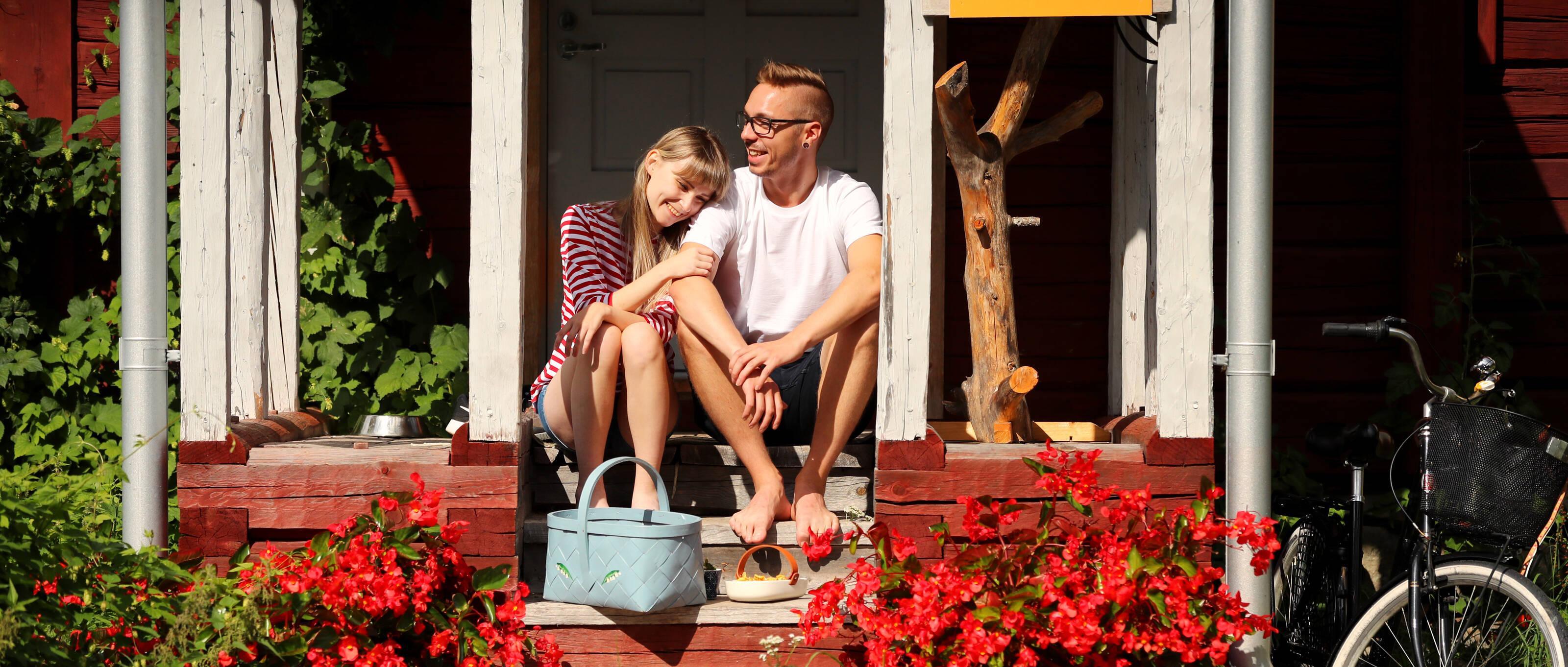 Un jeune couple est assis sur le porche d’une maison