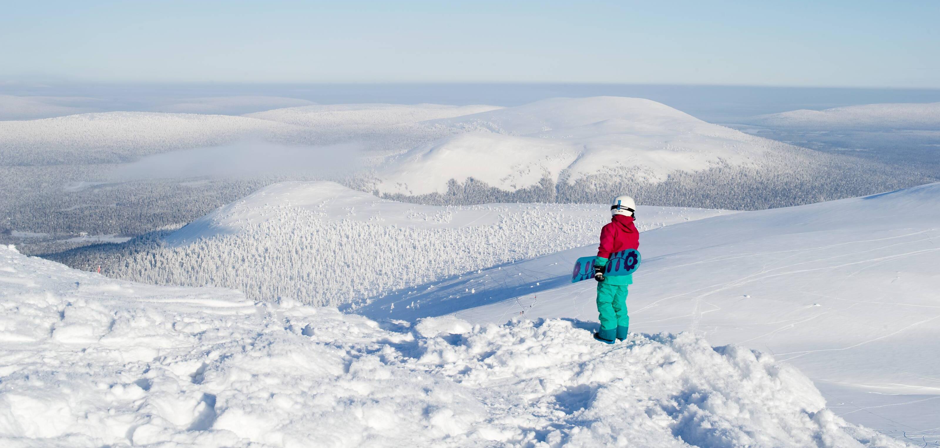 Snowboarders admiring a snowy fell landscape.