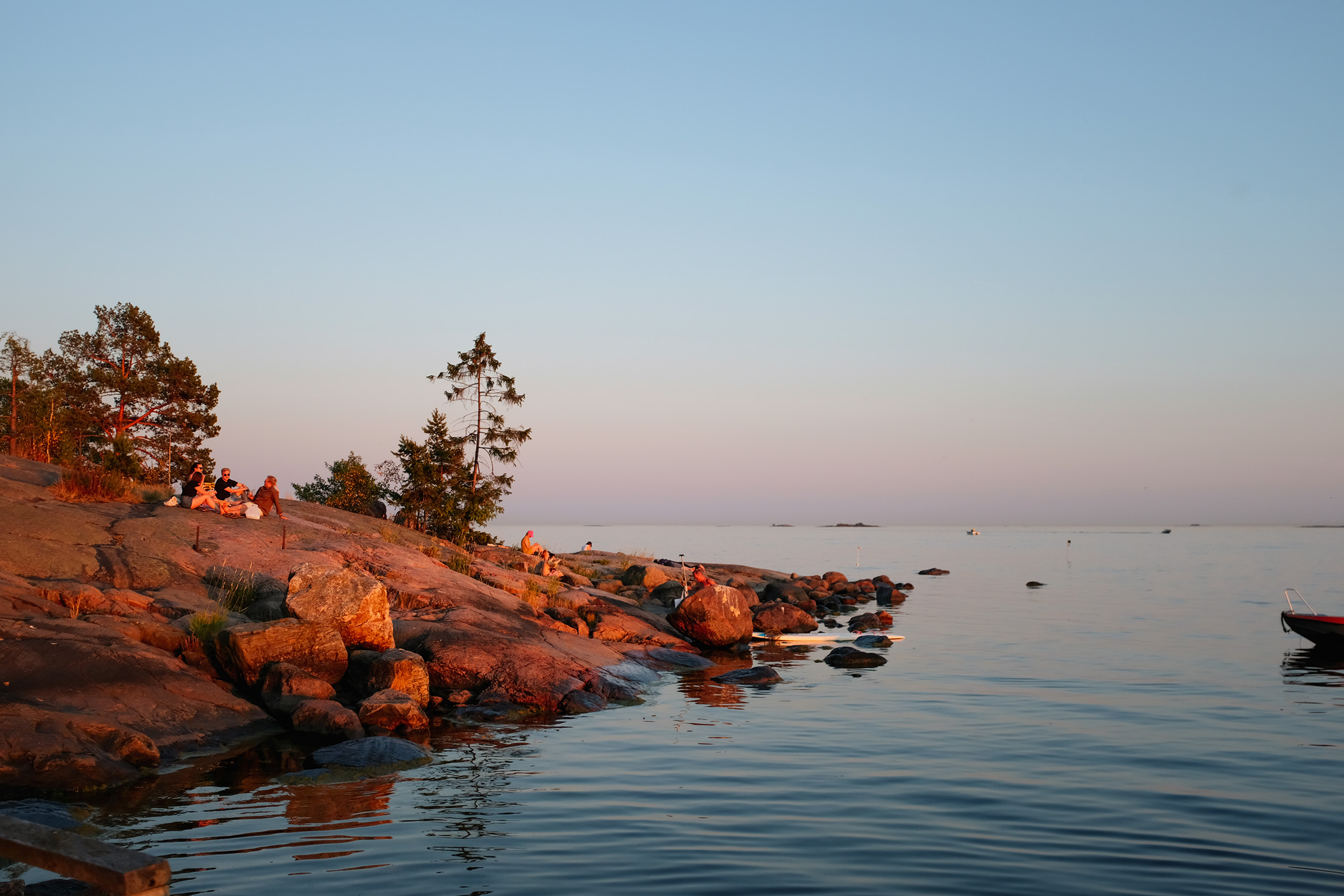 Un sereno paisaje marino de Helsinki iluminado por el fascinante resplandor del sol de medianoche.