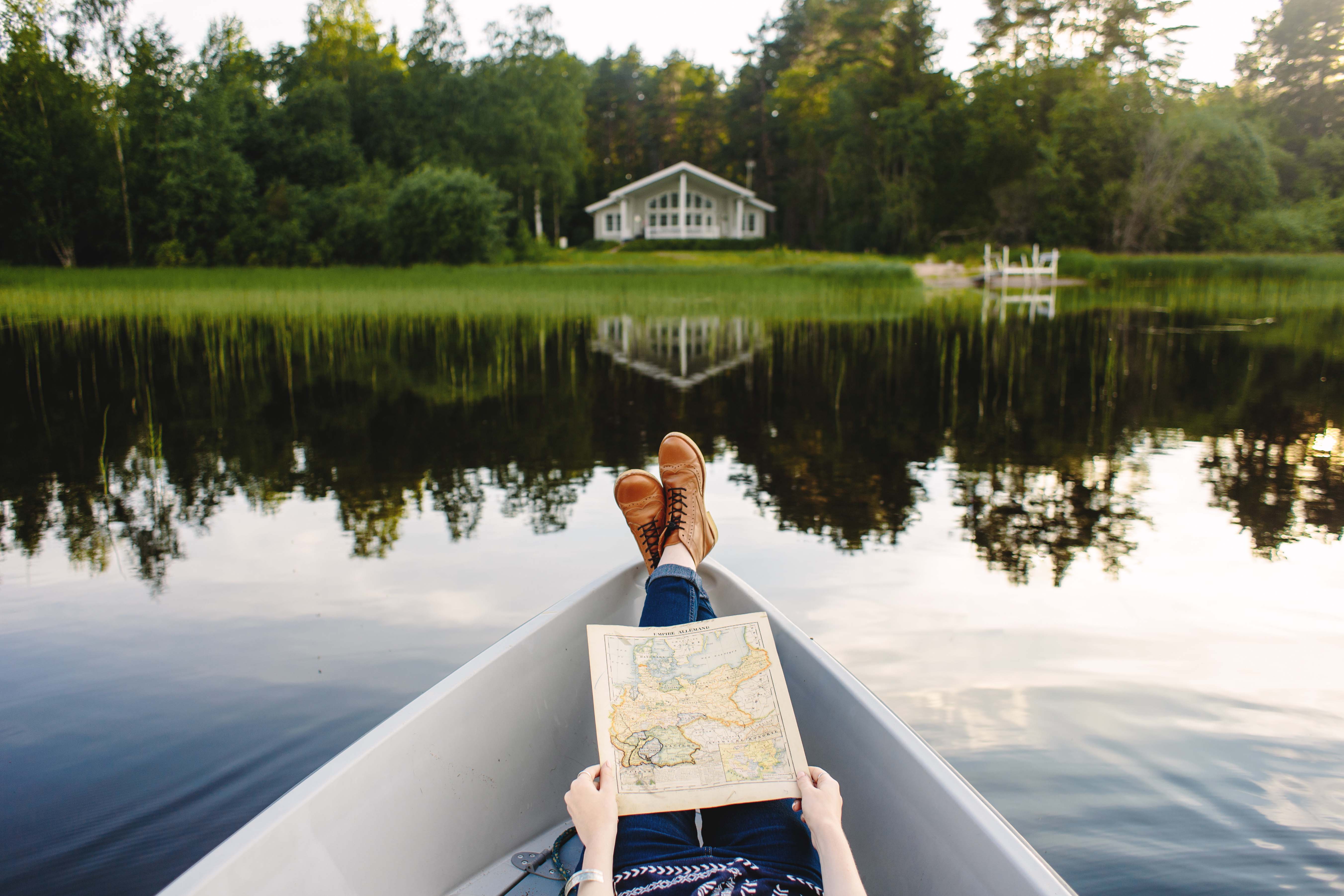 Una persona tumbada en una barca frente a un paisaje de lagos en Finlandia.